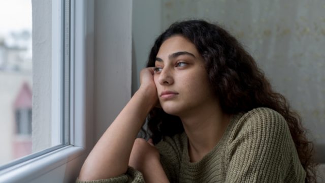 Young woman lost in thought, looking out of the window