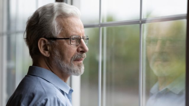 Pensive elderly mature senior man in eyeglasses, looking in distance.