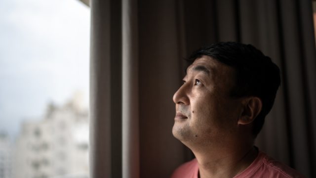 Mature man looking through window at home